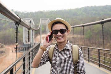 Young man using phone and selfie on bridge.