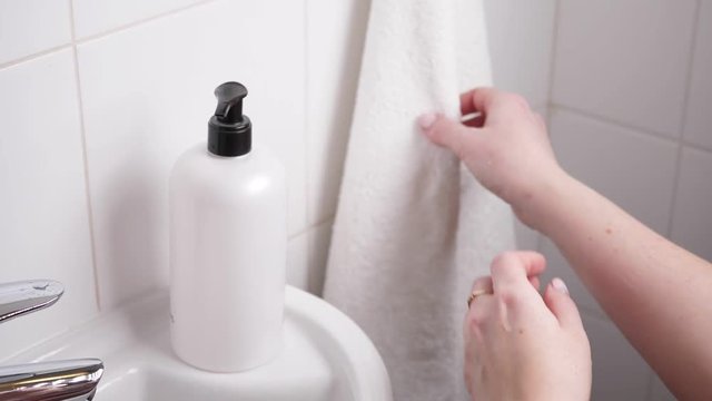 Woman drying hands with towel after washing in bathroom