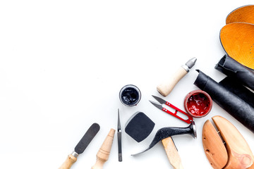 Work desk of shoemaker with instruments, wooden shoe and leather. White background top view copy...