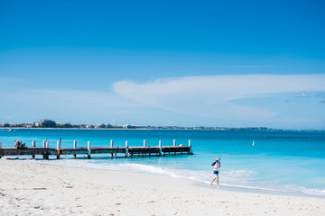 man running next to pier in beautiful beach with turquoise water in Grace Bay, Providenciales, Turks and Caicos