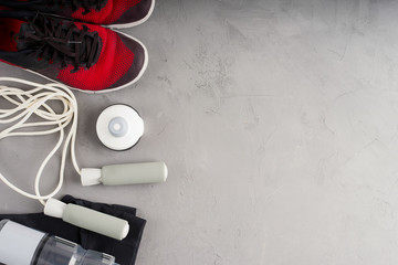 Fitness and sport equipment on a concrete background, top view. Set for sports and red sneakers on a gray background. Fitness concept background with space for your text.