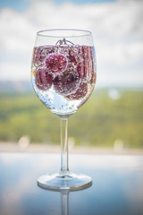 sweet cherry in a glass of sparkling soda water, healthy drinking concept.Refreshing summer drinks.summer bright fruit cocktails, lemonade on blur background. Vertical image