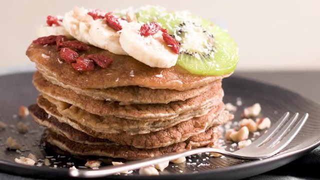 Healthy breakfast table,  homemade pancakes with kiwi, banana, goji and walnuts.