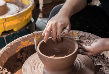 hands of a potter, creating an earthen jar on the circle
