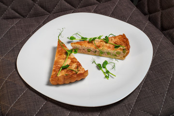 Two slices of salmon puff pie with peas and greens