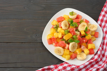 Bowl of healthy citrus fruit salad on dark wooden background. Top view.