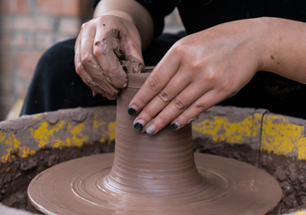 hands of a potter, creating an earthen jar on the circle