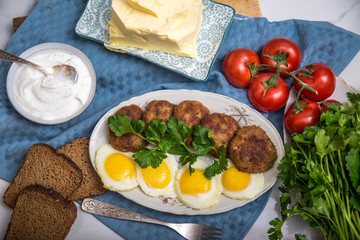 Meatballs and eggs with tomato, bread and greens