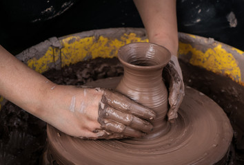 hands of a potter, creating an earthen jar on the circle