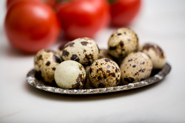 Obraz premium Quail eggs on white marble background with red tomatoes