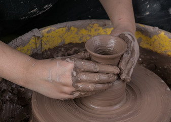 hands of a potter, creating an earthen jar on the circle