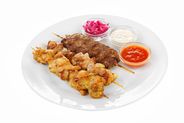Shish kebab, beef, lamb, pork, chicken meat on the grill, barbecue, without garnish on a plate, isolated on white background. Marinated onion, mayonnaise, tar tar, ketchup, tomato sauce Side view