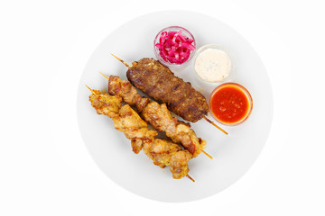 Shish kebab, beef, lamb, pork, chicken meat on the grill, barbecue, without garnish on a plate isolated on white background. Marinated onion, mayonnaise, tar tar, ketchup, tomato sauce View from above