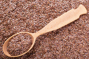 flax seeds in a wooden spoon, against the background of flax seeds