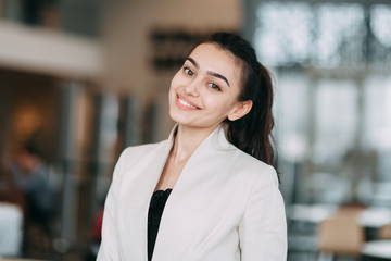 Beautiful Russian business girl standing with arms crossed and smiling. Office style and business image, business meeting and greeting