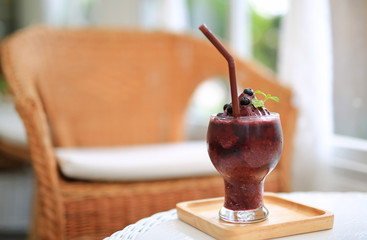 Glass of fresh blueberry smoothie on the wood table at the cafe.