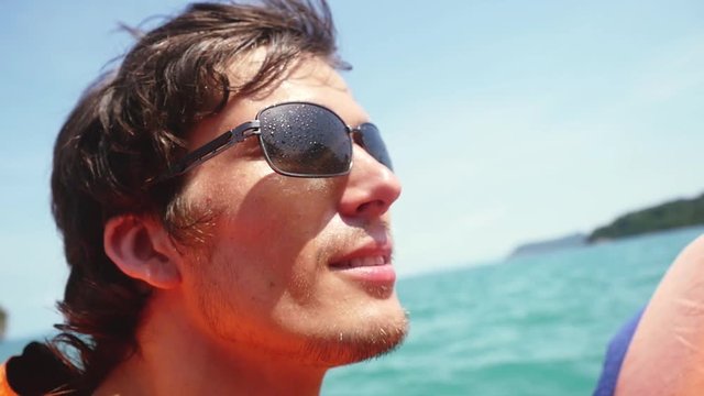 Young handsome man in sunglasses and life jacket enjoying a sailing trip on the sea. slow motion. Vacation concept. 1920x1080