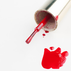 Nail varnish. To paint the nails. Red and blue nail polishes spilled over white background