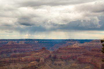 Skyline above the grand canyon. Beautiful Grand Canyon shapes under the dark stormy clouds with rain somewhere in the far horizon.