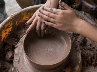 hands of a potter, creating an earthen jar on the circle