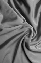 Naklejka na ściany i meble Background of fabric, twisted folds on a textured gray fabric.