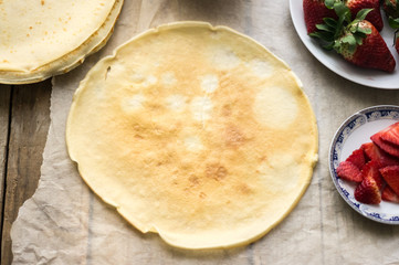 Freshly cooked homemade pancake with fresh ricotta cheese and strawberries on a side