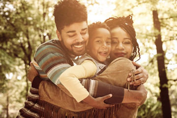 African American family hugging in park.
