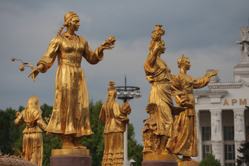 Fototapeta na wymiar Golden statue in Moscow park. Women with a flowers in her hand