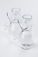 Opened transparent bottles with mineral water closeup on soft  white wood background.