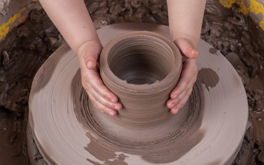 hands of a potter, creating an earthen jar on the circle