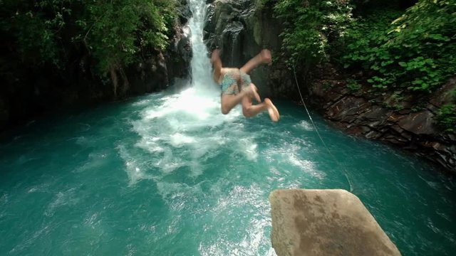 Man jumping in the river with waterfall slow mo