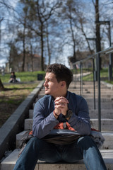 Obraz premium young man sitting on steps in park 