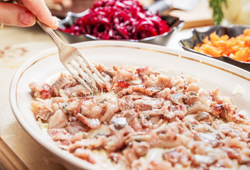 preparing russian traditional salad 'herring under fur coat'