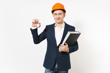Young smiling businessman in dark suit, protective hardhat holding black folder for papers document and alarm clock isolated on white background. Time is running out. Male worker for advertisement.