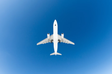 Passenger airplane. View exactly from below, white silhouette against the blue sky.