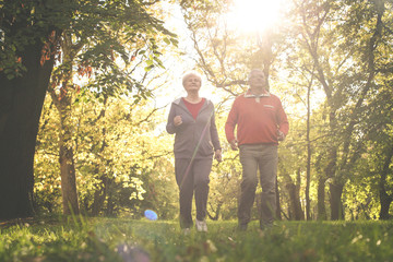 Naklejka na ściany i meble Active seniors couple in sports clothing jogging together in park.