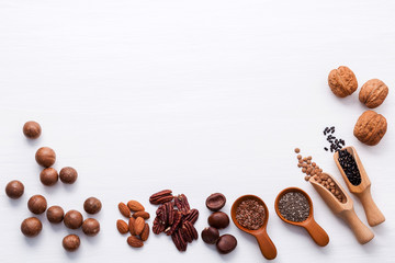Spoon of various legumes and different kinds of nuts walnuts kernels ,hazelnuts, macadamia ,almond kernels,brown pinto ,red kidney beans and pecan set up on white wooden table.