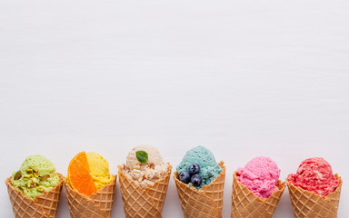 Various of ice cream flavor in cones blueberry ,strawberry ,pistachio ,almond ,orange and cherry setup on white wooden background . Summer and Sweet menu concept. - 199405452