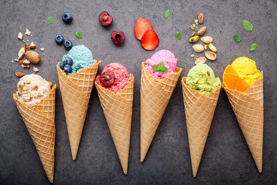 Various of ice cream flavor in cones blueberry ,strawberry ,pistachio ,almond ,orange and cherry setup on dark stone background . Summer and Sweet menu concept.