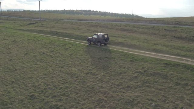 Aerial view of a jeep driving on a countryside road