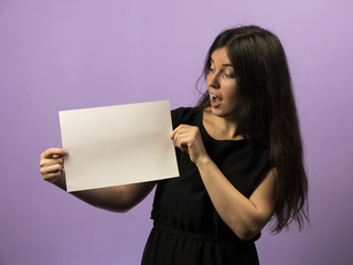 Surprised Young Brunette Girl holding empty blank white board. Leaflet presentation. Pamphlet hold...