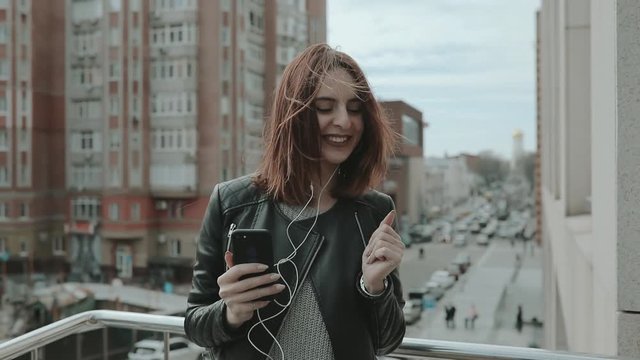 Rock style woman dancing listening to music in city