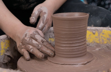 hands of a potter, creating an earthen jar on the circle