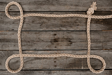 top view of nautical rope with knot on grunge wooden surface