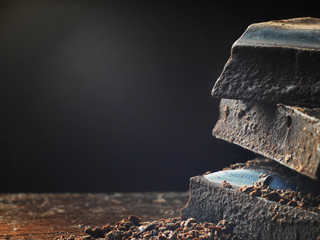 Black chocolate close-up, macro photo. Pieces of dark chocolate on a wooden background.