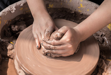 hands of a potter, creating an earthen jar on the circle