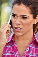 Young Diverse Adult Female Using Cell Phone And Unhappy Wearing Pink Shirt