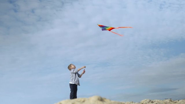 kid playing with a kite standing on a rocky shore