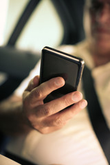 Business man in car. Senior man using smart phone in taxi. focus is on hand.