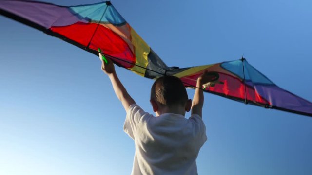Little child plays with a kite on blue sky background. concept of dream flight